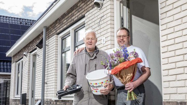 Vader en zoon De Jong bij de voordeur van hun nieuwe huurhuis.