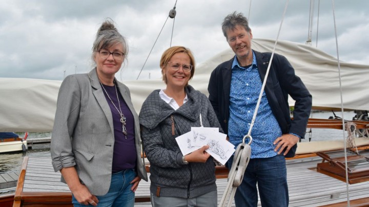 Annemarie Oost (midden) ontving het eerste setje kaarten van ondernemers Eddy van der Noord en Henriët van der Horst.