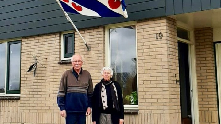 Wim en Marijke poseren voor hun woning aan It Roer, waar vandaag de vlag wappert.
