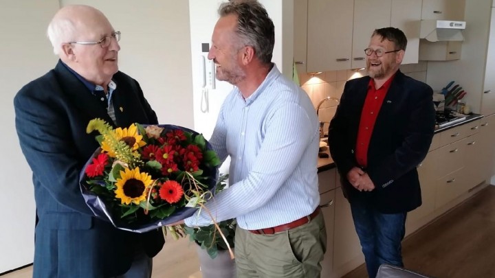 Jelle van der Bijl kreeg het speldje en bloemen van zoon Hendrik-Dirk. Arie van Barneveld kijkt lachend toe. (Foto: Alinda Talsma)